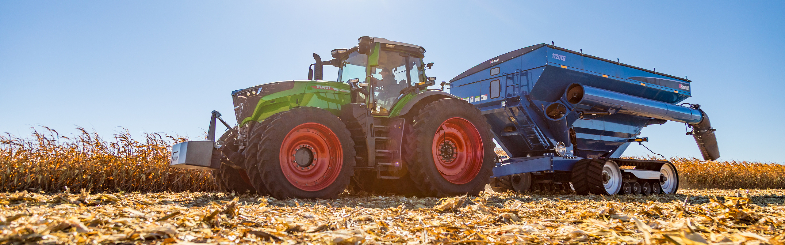 Fendt 1000 Vario tractor pulling a grain cart in a corn field Fendt 1000 Vario tractor pulling a grain cart in a corn field
