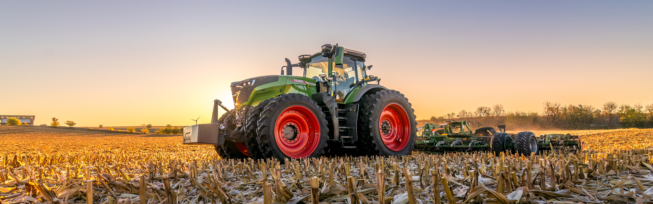 Fendt 1000 Vario Tractor pulling tillage in the field at sunset