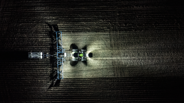 Fendt 1000 Vario shining lights on the field at night Aerial shot of Fendt 1000 Vario shining lights on the field at night