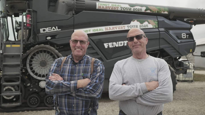Two men standing in front of the Fendt  IDEAL  Combine