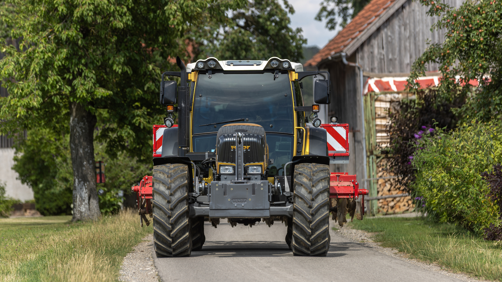 A golden Fendt 200 Vario from the front on a road.