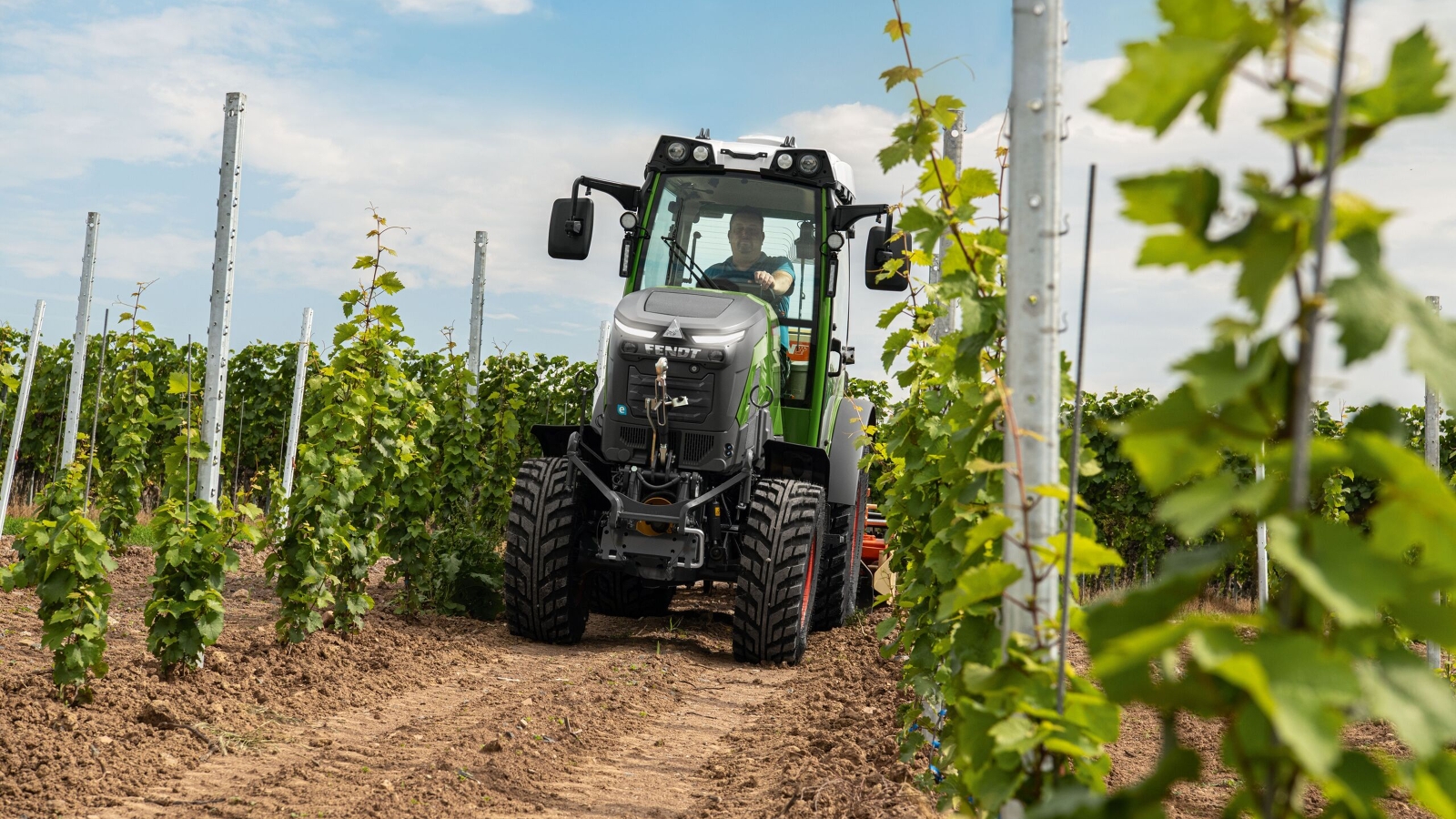 The Fendt e100 V Vario driving a seed drill in the vineyard