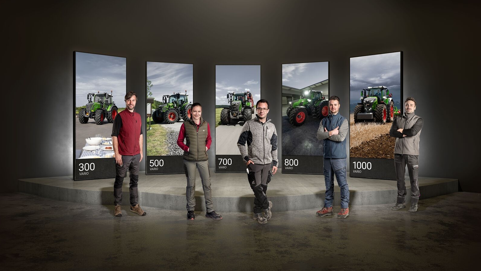 5 people standing next to each other, behind them, large screens with the Fendt 300, 500, 700, 800 and 1000 Vario.