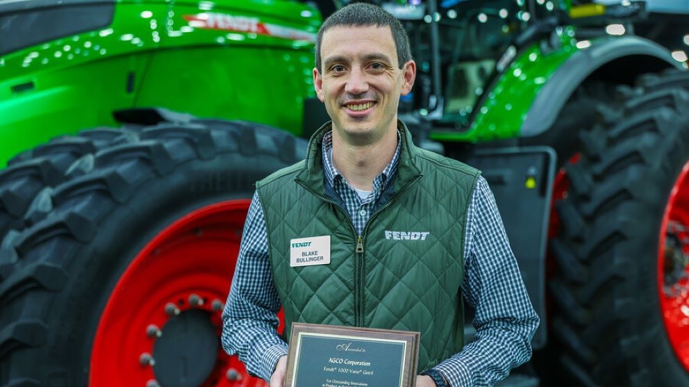 Fendt tractor specialist holds the AE50 award in front of the Fendt 1000 Vario Tractor