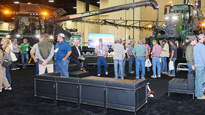 Farmers at the Fendt booth with the Fendt Rogator and IDEAL combine in the background