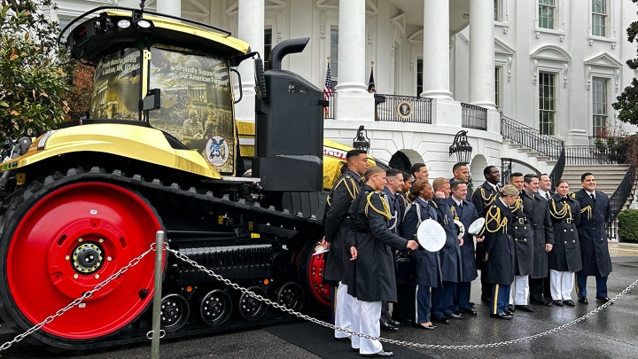 American Service Men and Women standing in front of the Gold Fendt Tractor at the White House