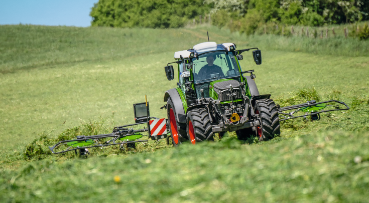 A FENDT 500 VARIO drives across a pasture.