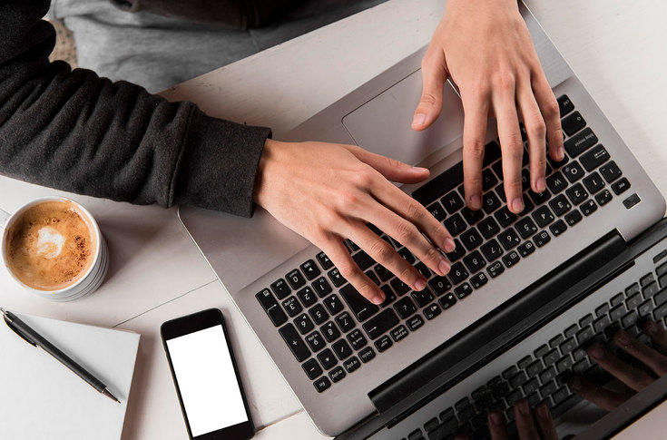 A person is typing on the keyboard of the laptop.