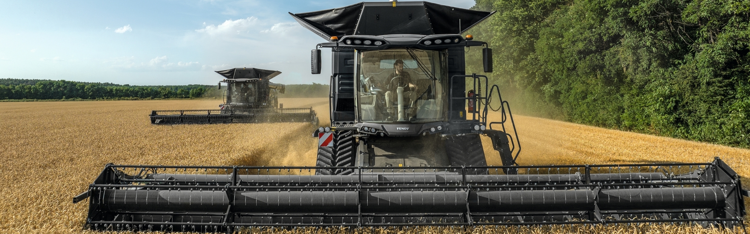 Fendt IDEAL from the front with activated lighting and dark clouds in the sky