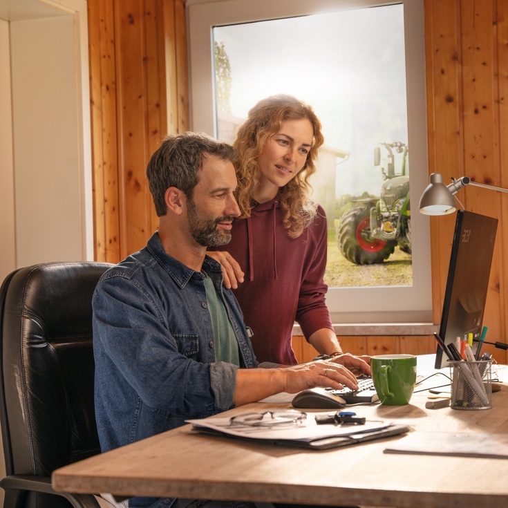 A farmer couple in front of their office computer, creating field boundaries with FendtONE Agronomy.