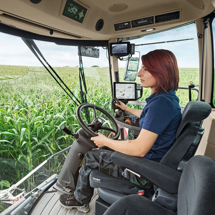 A farmer sits in her Fendt Katana and steers the machine through a maize field.