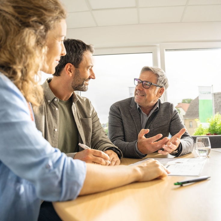 A farmer and farmer sit at a table with a Fendt dealer and get advice.