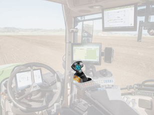 Interior view of a modern agricultural vehicle with focus on an ergonomically shaped multifunction joystick.